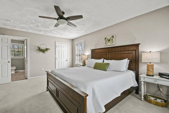 bedroom featuring baseboards, ceiling fan, light carpet, and connected bathroom
