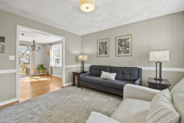 living room featuring baseboards, a notable chandelier, and wood finished floors