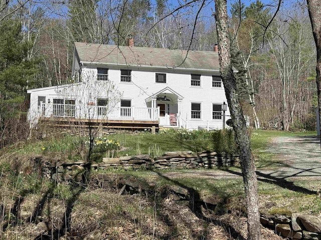 colonial house featuring a wooden deck and a chimney