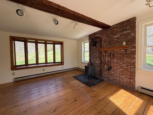 unfurnished living room featuring a wood stove, wood-type flooring, plenty of natural light, a baseboard radiator, and beamed ceiling