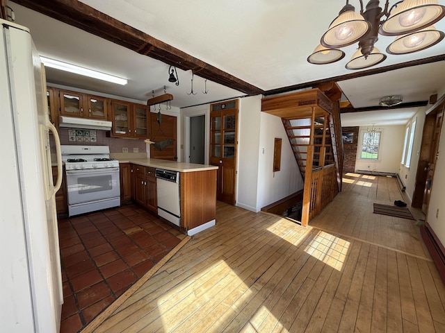 kitchen with a peninsula, white appliances, light countertops, under cabinet range hood, and a notable chandelier