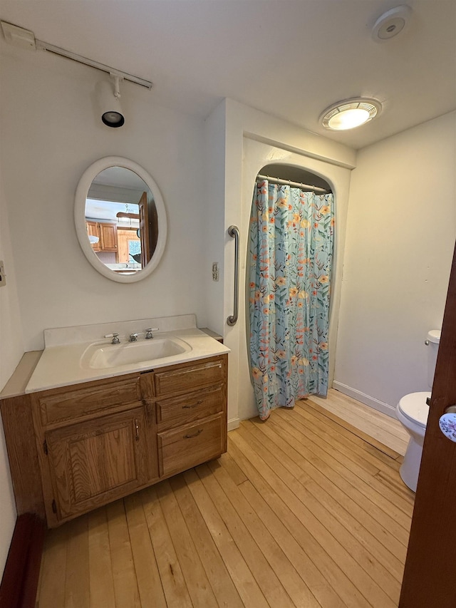 full bath with vanity, toilet, a shower with shower curtain, hardwood / wood-style flooring, and rail lighting