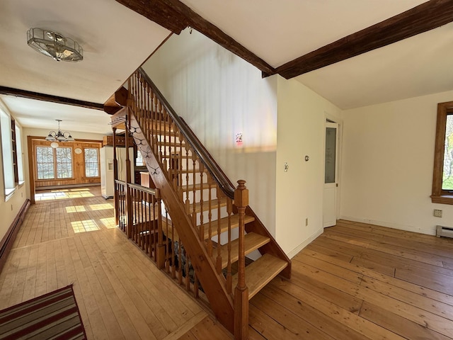 stairs with baseboards, beam ceiling, hardwood / wood-style floors, and a chandelier