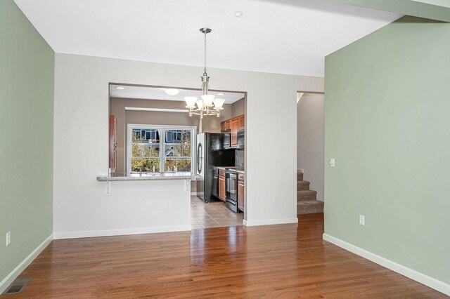 interior space featuring stairs, baseboards, a notable chandelier, and wood finished floors