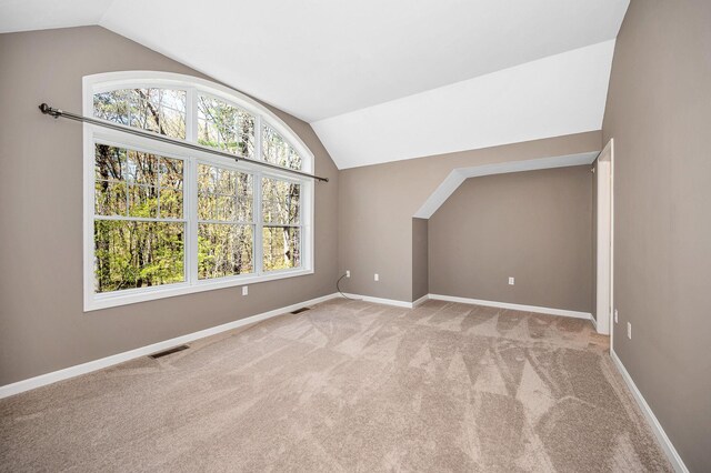 bonus room with visible vents, baseboards, lofted ceiling, and light carpet