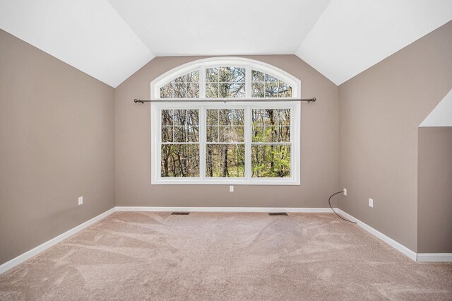 spare room with carpet flooring, baseboards, and vaulted ceiling
