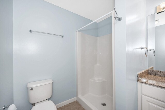 full bathroom featuring vanity, tile patterned flooring, toilet, baseboards, and walk in shower