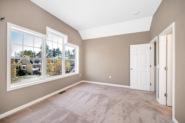 unfurnished bedroom featuring visible vents, baseboards, carpet, and lofted ceiling