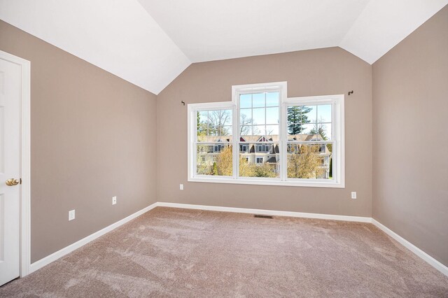 interior space with baseboards, vaulted ceiling, carpet flooring, and visible vents