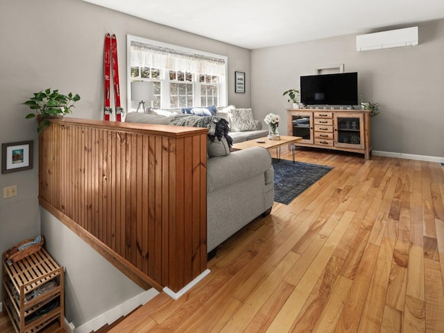 living area with baseboards, a wall mounted air conditioner, and hardwood / wood-style flooring