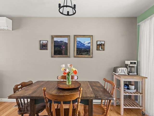 dining space with an inviting chandelier, light wood-style flooring, and a wall mounted AC