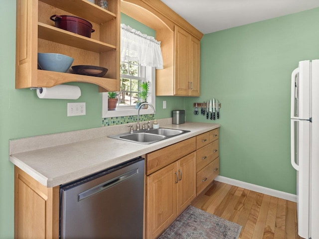 kitchen featuring a sink, light countertops, freestanding refrigerator, light wood-type flooring, and stainless steel dishwasher