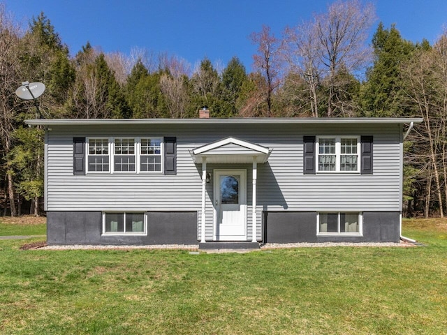 bi-level home featuring a chimney and a front lawn
