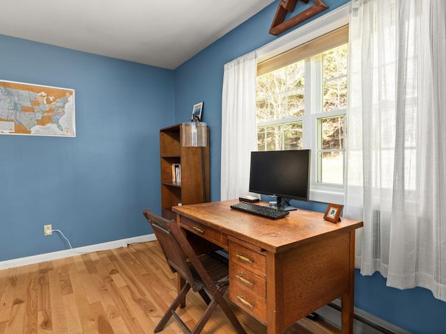 office area featuring baseboards, light wood finished floors, and a wealth of natural light