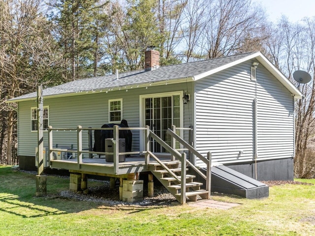 rear view of property with a lawn, a chimney, a shingled roof, and a deck
