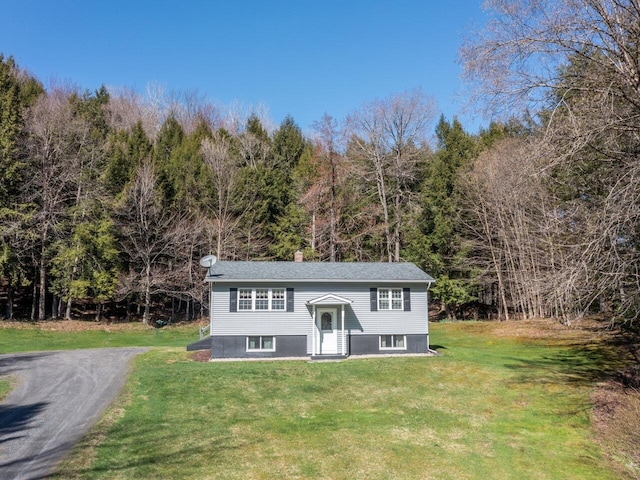 raised ranch with a forest view and a front lawn