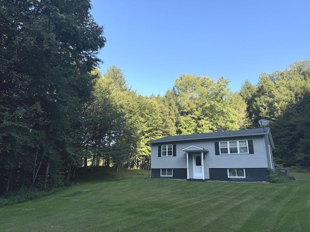 bi-level home with a front lawn and a wooded view