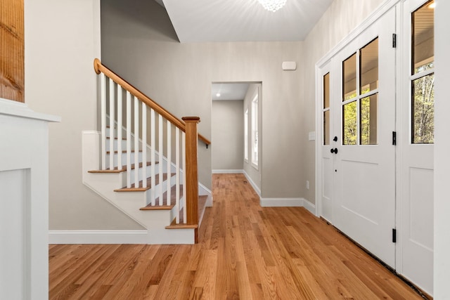 foyer featuring baseboards, stairs, and wood finished floors
