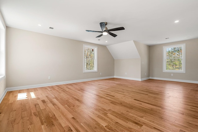 bonus room featuring light wood-style floors, baseboards, a ceiling fan, and a healthy amount of sunlight