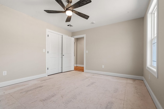 unfurnished bedroom featuring baseboards, ceiling fan, visible vents, and a closet