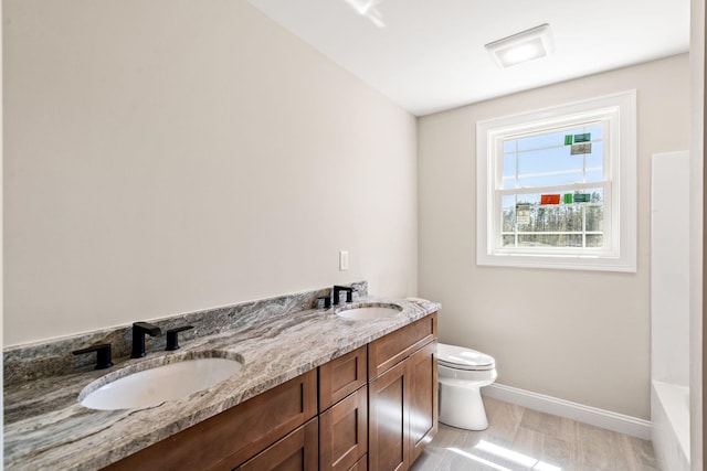 bathroom with toilet, baseboards, a tub, and a sink