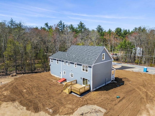 exterior space with roof with shingles and a wooded view