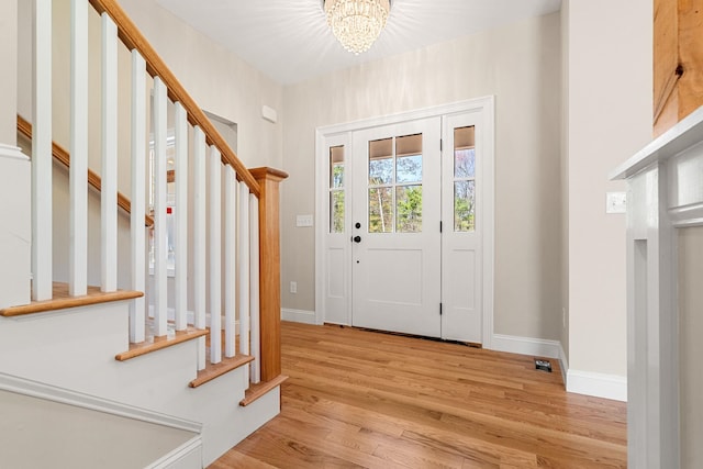 foyer entrance with stairs, baseboards, a notable chandelier, and light wood-style floors
