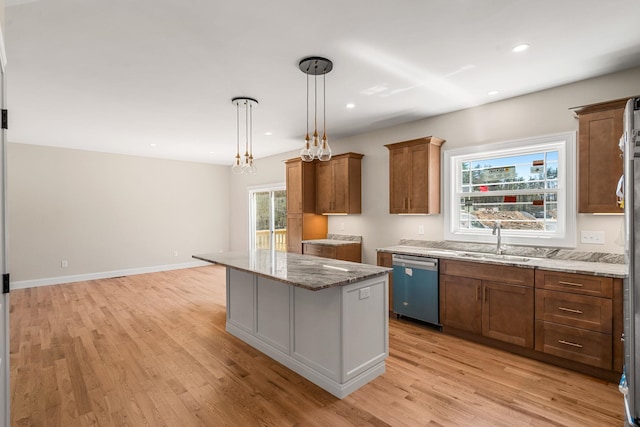 kitchen with brown cabinets, light wood-style floors, a sink, and dishwasher