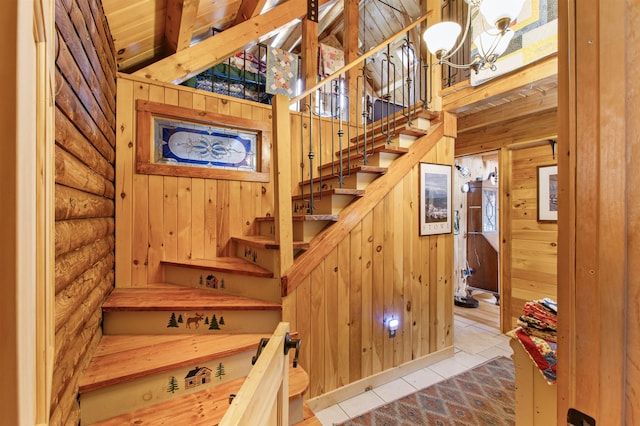 staircase featuring wood walls, tile patterned floors, and a notable chandelier