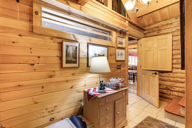 hall featuring an inviting chandelier, log walls, light tile patterned floors, and wooden walls