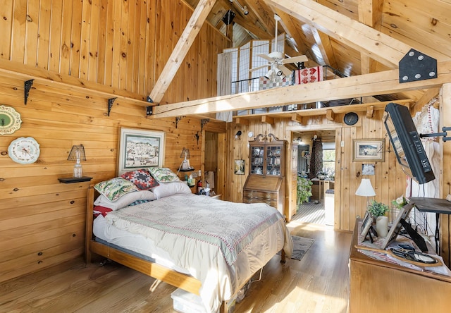 bedroom with beam ceiling, wood walls, wood finished floors, and high vaulted ceiling