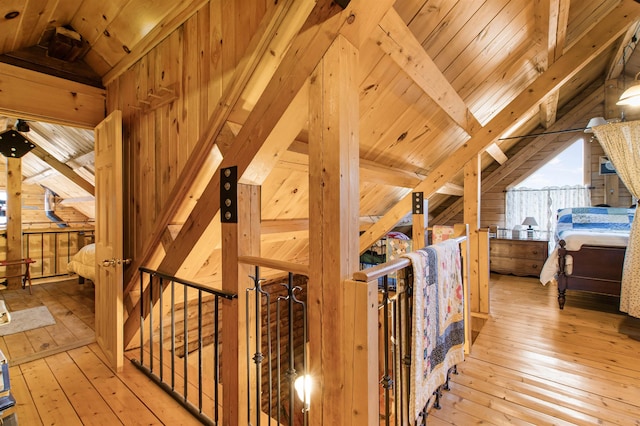 bedroom featuring lofted ceiling with beams, light wood-style flooring, and wooden walls