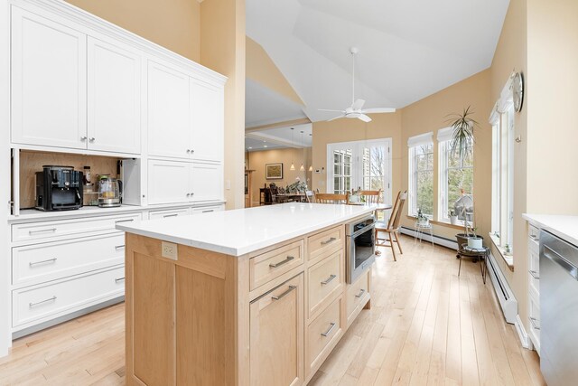 kitchen with ceiling fan, light countertops, light wood-style flooring, stainless steel appliances, and a kitchen island
