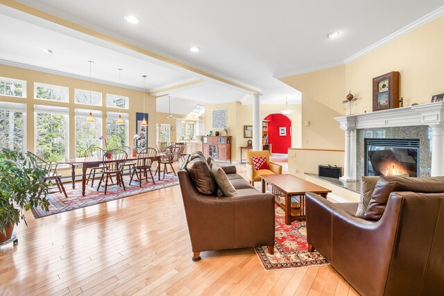 living room with crown molding, a fireplace, recessed lighting, and light wood-style flooring