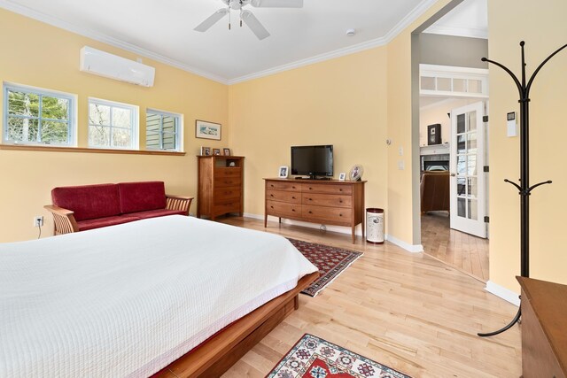 bedroom with ornamental molding, baseboards, light wood-type flooring, a wall mounted AC, and a ceiling fan