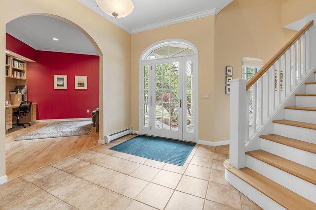 foyer featuring tile patterned flooring, arched walkways, baseboards, a baseboard heating unit, and ornamental molding