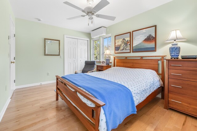 bedroom featuring an AC wall unit, a closet, baseboards, and light wood-style floors