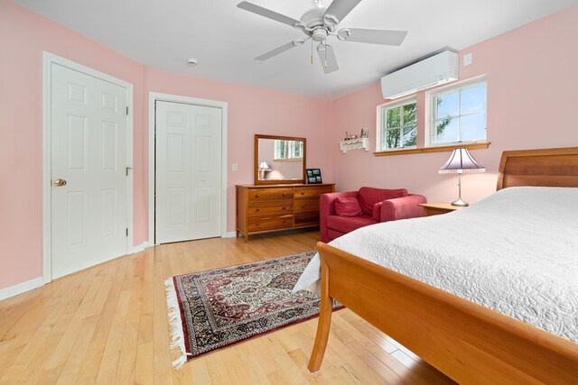 bedroom with baseboards, a wall unit AC, a ceiling fan, and wood-type flooring