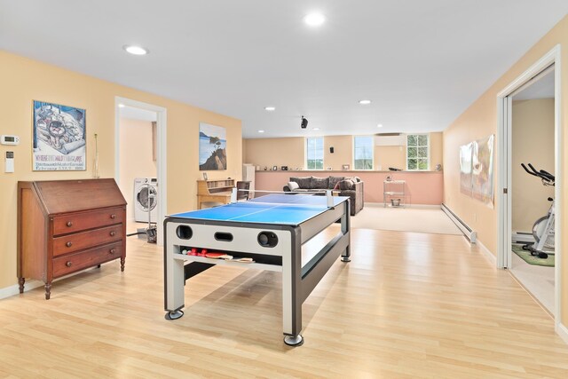playroom with washing machine and clothes dryer, recessed lighting, light wood finished floors, and a baseboard radiator