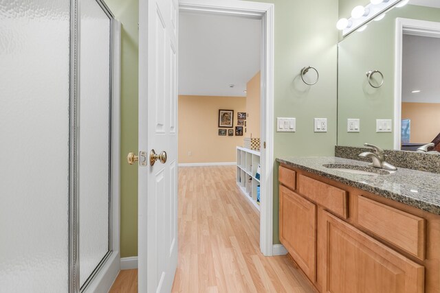 full bath with vanity, baseboards, an enclosed shower, and wood finished floors