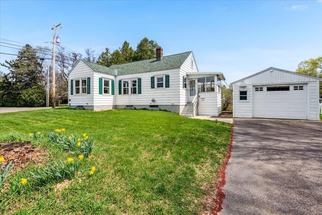 ranch-style house with a chimney, a front yard, an outbuilding, a detached garage, and aphalt driveway
