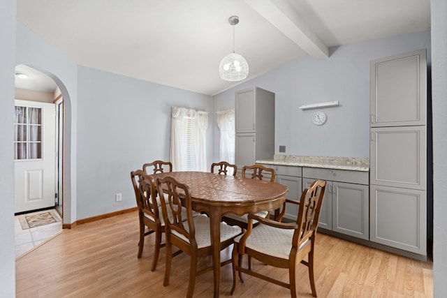 dining space with vaulted ceiling with beams, arched walkways, light wood-style flooring, and baseboards
