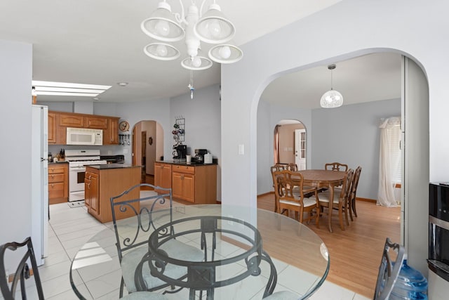 dining room featuring an inviting chandelier, arched walkways, and light tile patterned flooring