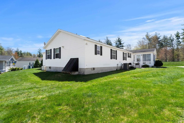 rear view of house with central air condition unit, a lawn, and a sunroom