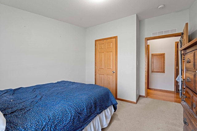 bedroom featuring baseboards, light colored carpet, and visible vents