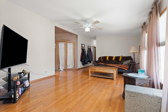 living area featuring baseboards, a ceiling fan, and light wood-style flooring