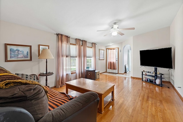 living room featuring arched walkways, ceiling fan, and light wood-type flooring