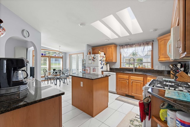 kitchen featuring a sink, a kitchen island, white appliances, and a healthy amount of sunlight