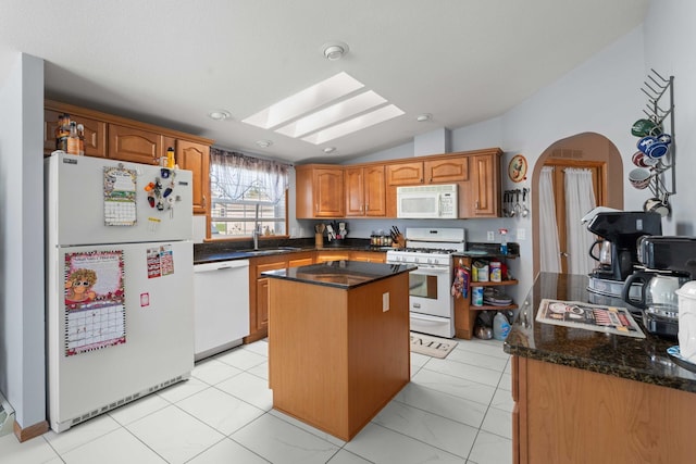 kitchen featuring a sink, white appliances, brown cabinetry, a center island, and lofted ceiling with skylight
