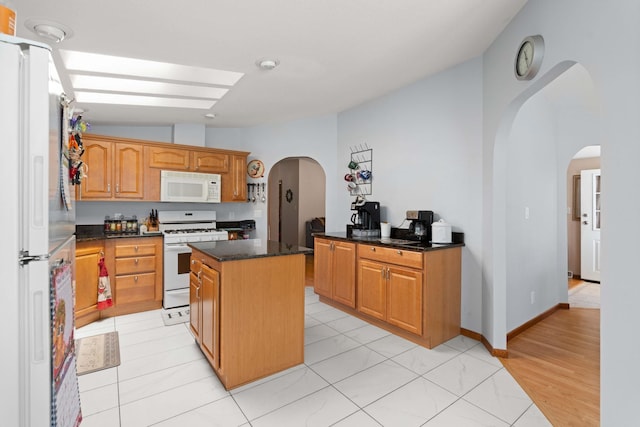 kitchen with arched walkways, a center island, vaulted ceiling, and white appliances